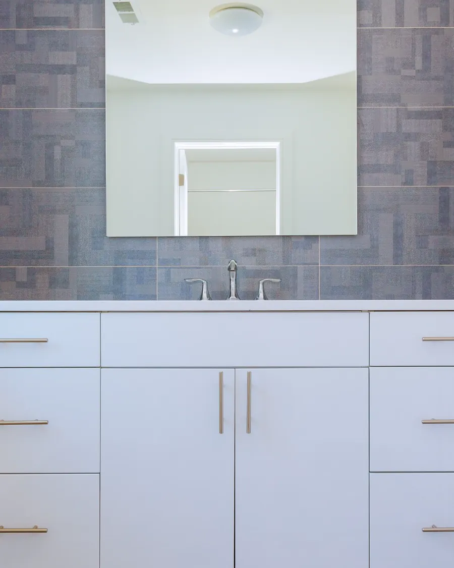Custom bathroom vanity with a stone counter, mirror and brushed hardware