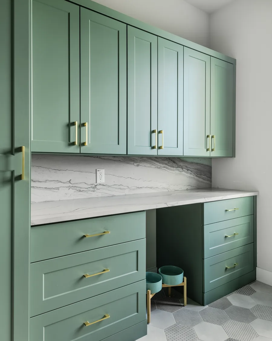 Green cabinetry with brass pulls, marble backsplash and a built-in counter