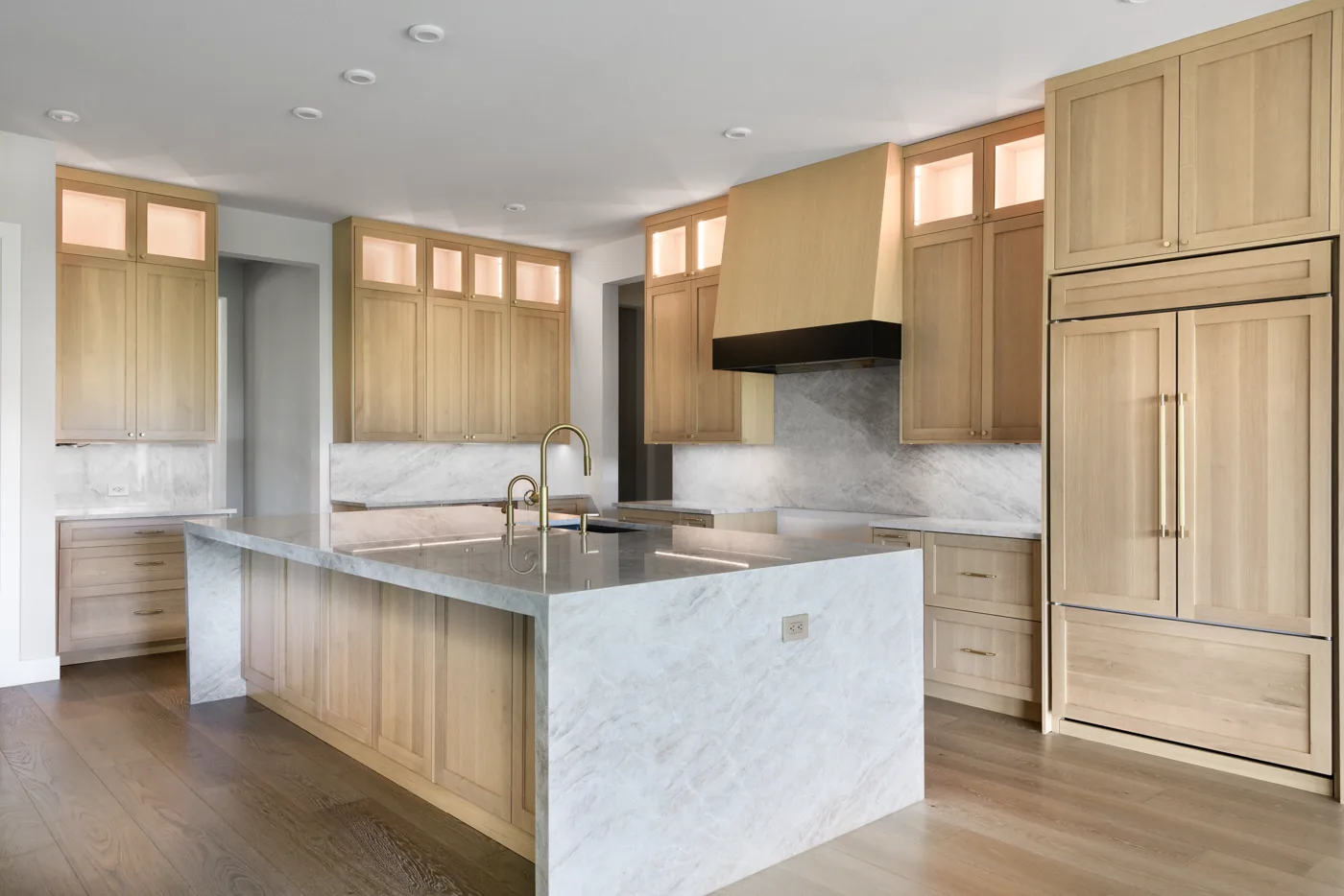 Kitchen with white oak cabinetry, a marble island and a full-height pantry run